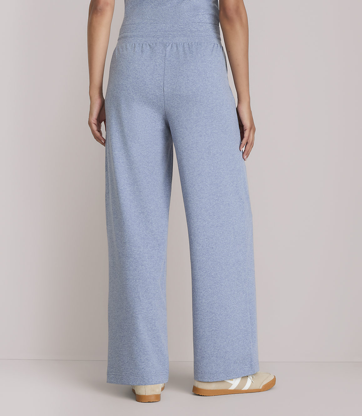 A person wearing light blue wide-leg lounge pants stands against a plain, light-colored background.