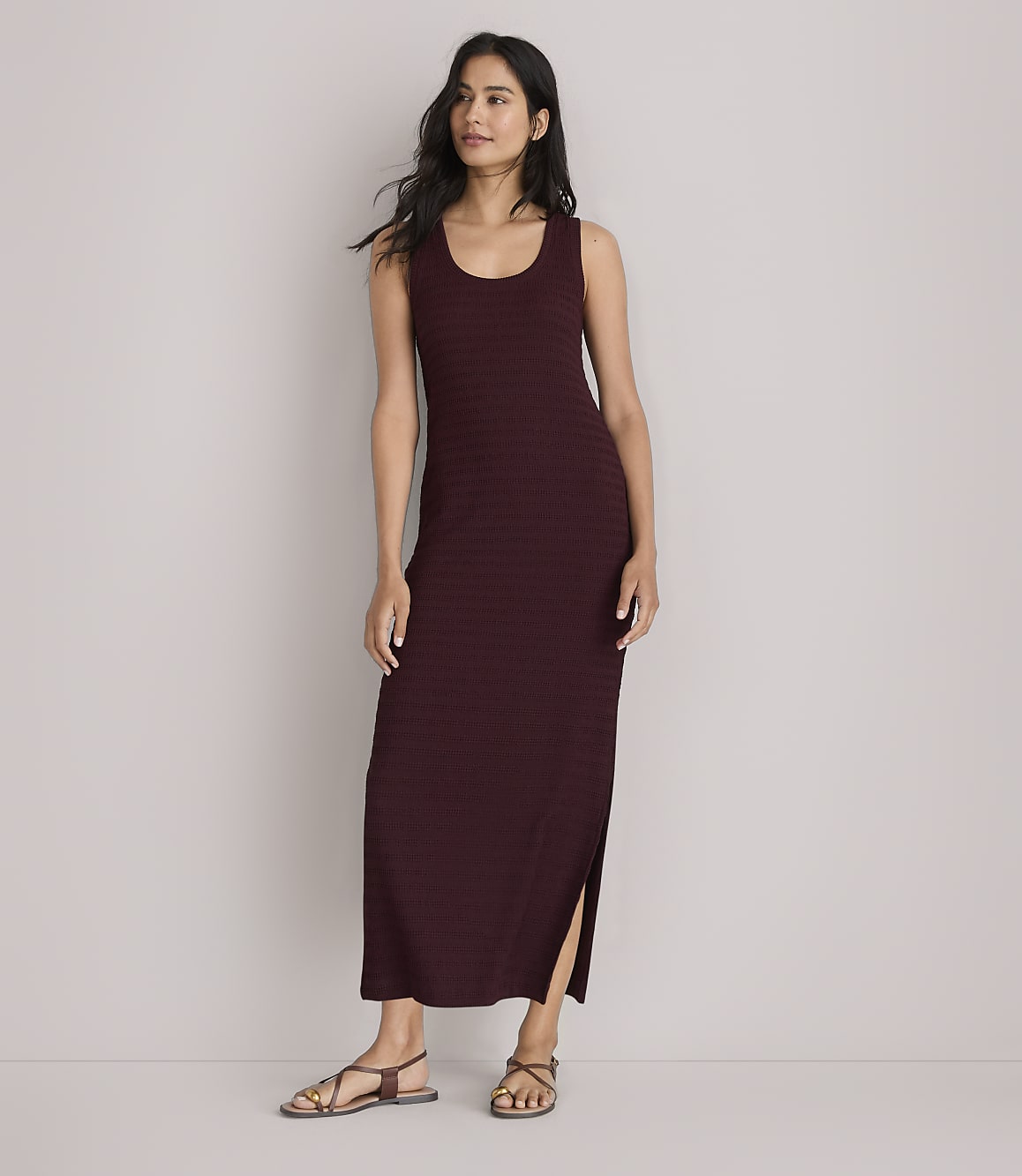 A woman in a maroon maxi dress stands against a plain white background.