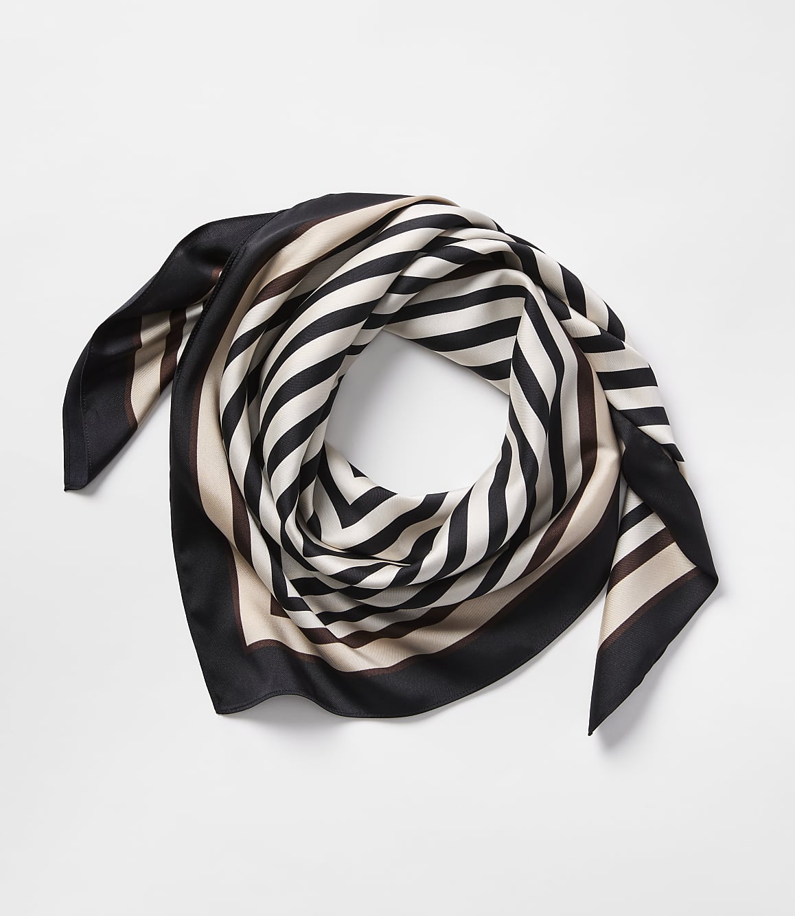 A silk scarf with black, white, and tan stripes is artfully folded on a plain white background.