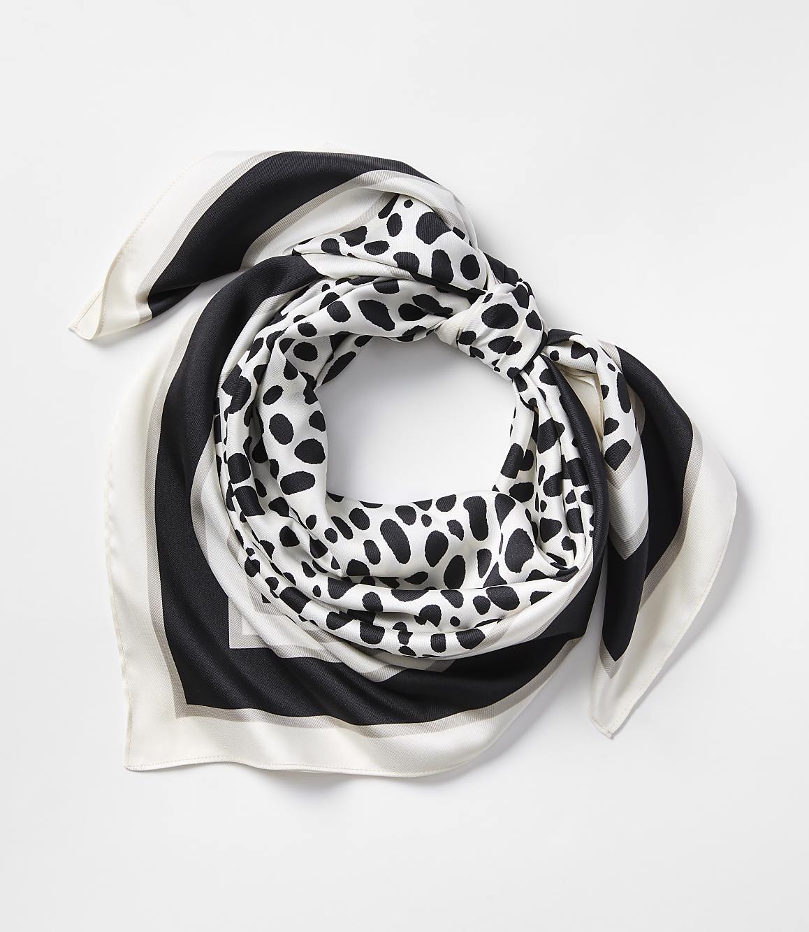 A black, white, and grey patterned silk scarf is neatly folded against a plain white background.