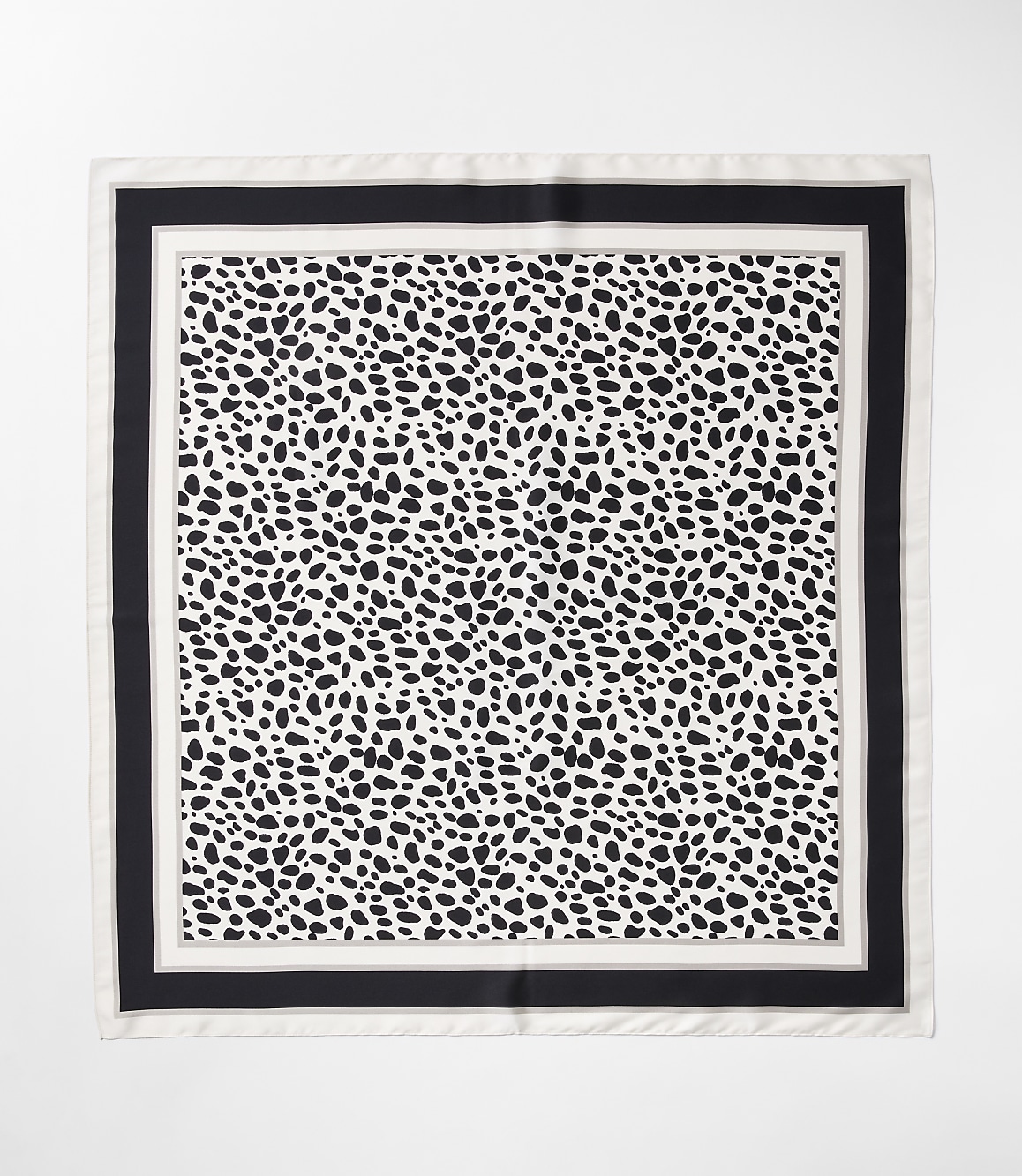 A black and white dalmatian-print scarf with a black border is laid flat against a white background.