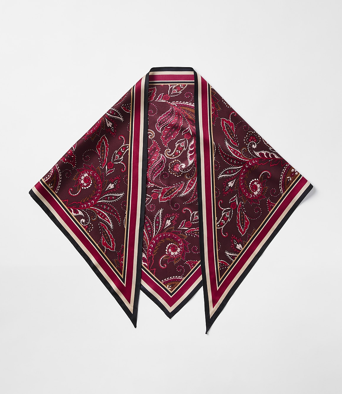 A maroon paisley-patterned silk scarf with a black and cream border lies flat against a plain white background.