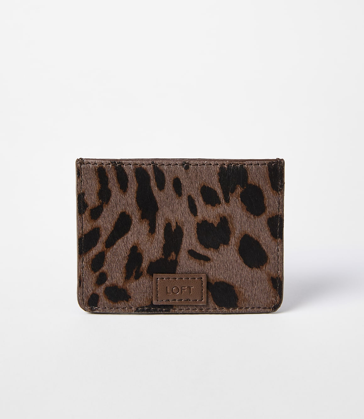 A small, brown leopard-print cardholder with a "LOFT" logo sits against a plain white background.