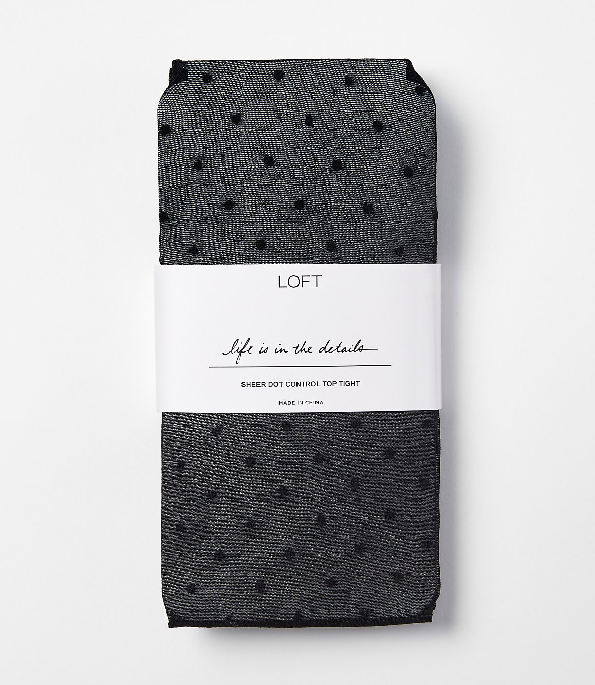 A pair of black sheer polka dot tights are neatly folded with a white band around them, set against a plain white background.