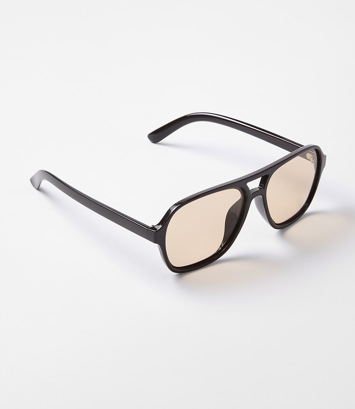 A pair of dark-rimmed aviator sunglasses with amber lenses rests on a plain white background.