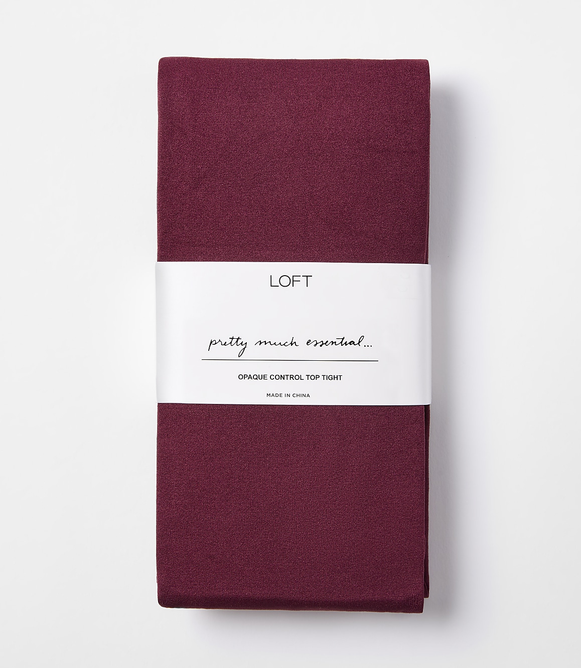 A folded pair of burgundy opaque control top tights with a white band displaying the brand "LOFT" and product details is presented against a plain white background.