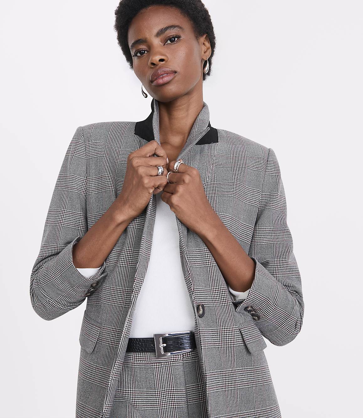 A woman in a plaid blazer and pants stands against a plain white background.