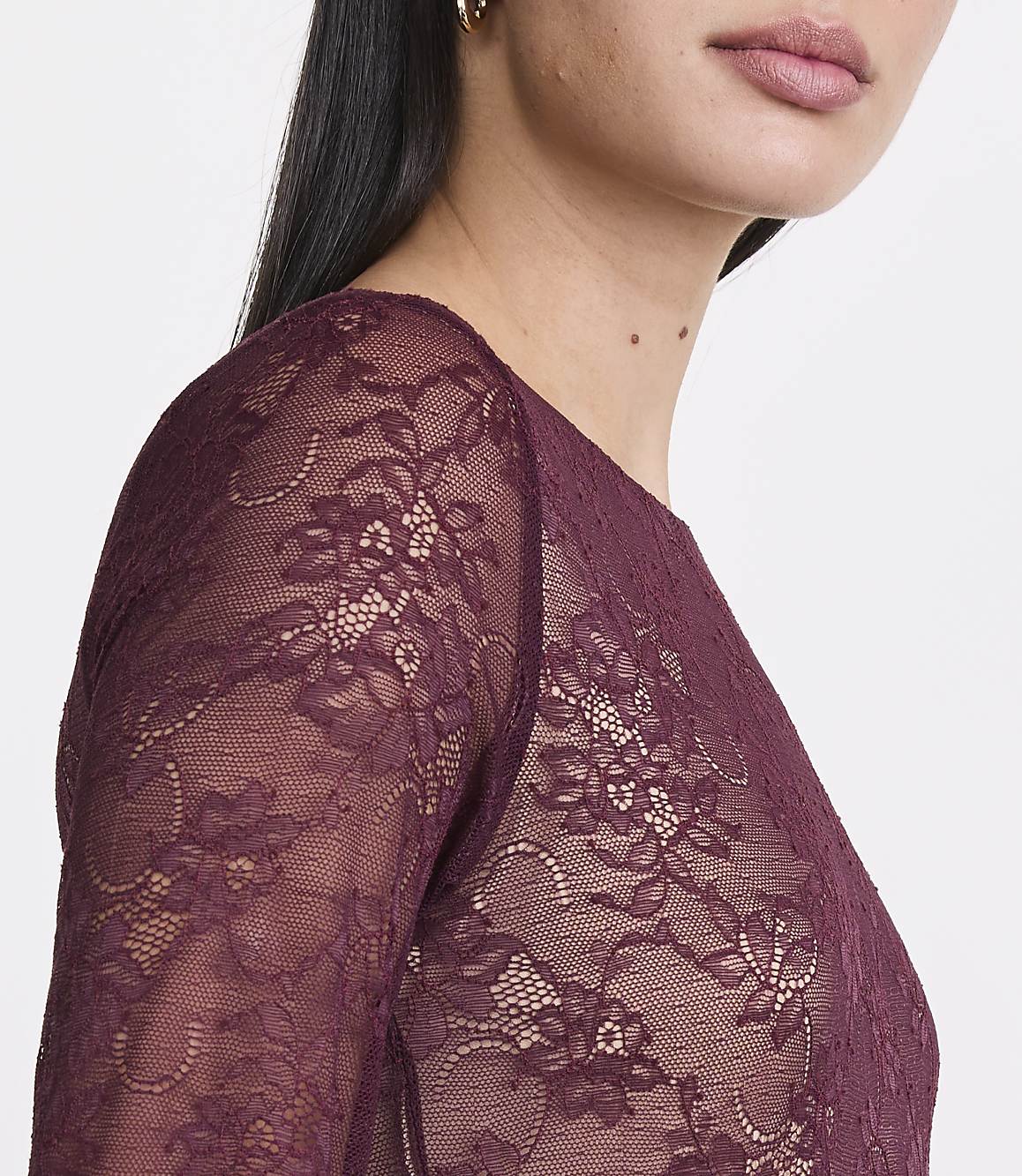 A woman in a burgundy lace top is shown from the chest up against a plain white background.