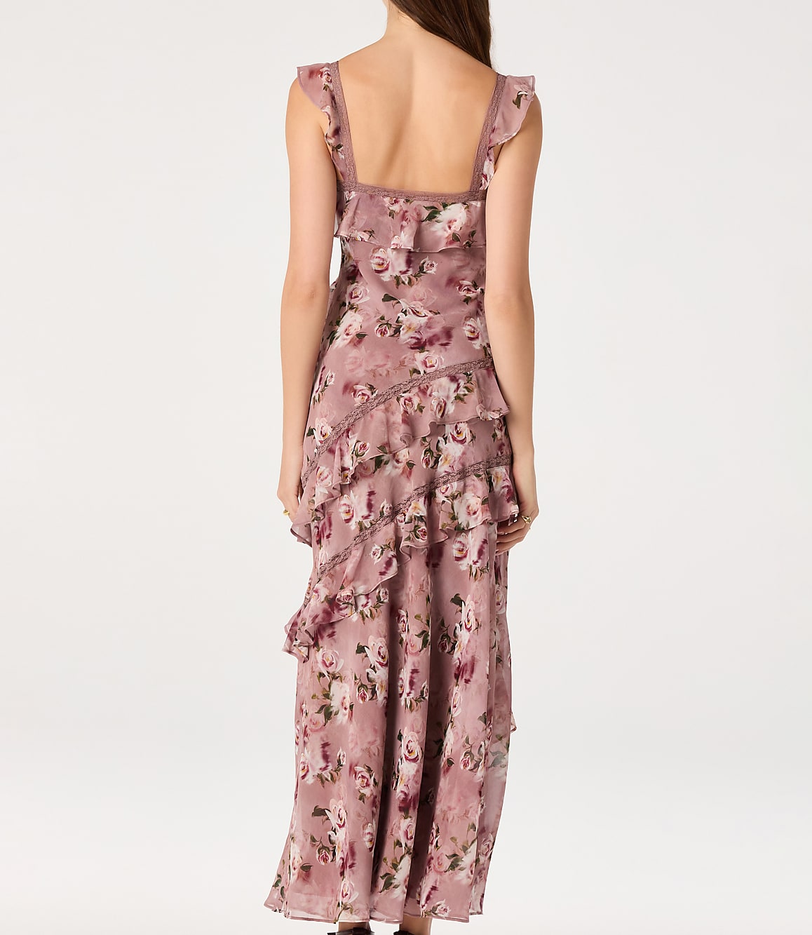 A woman in a ruffled, floral-print dress stands against a plain white background.