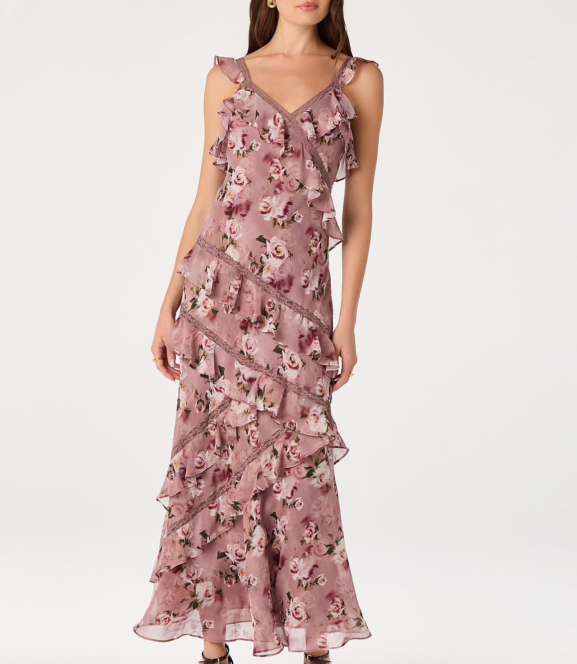A woman in a ruffled, floral-print dress stands against a plain white background.