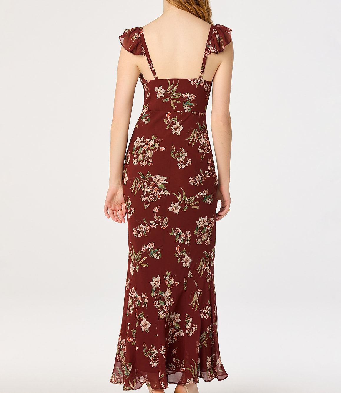 A woman in a floral print dress stands against a plain white background.