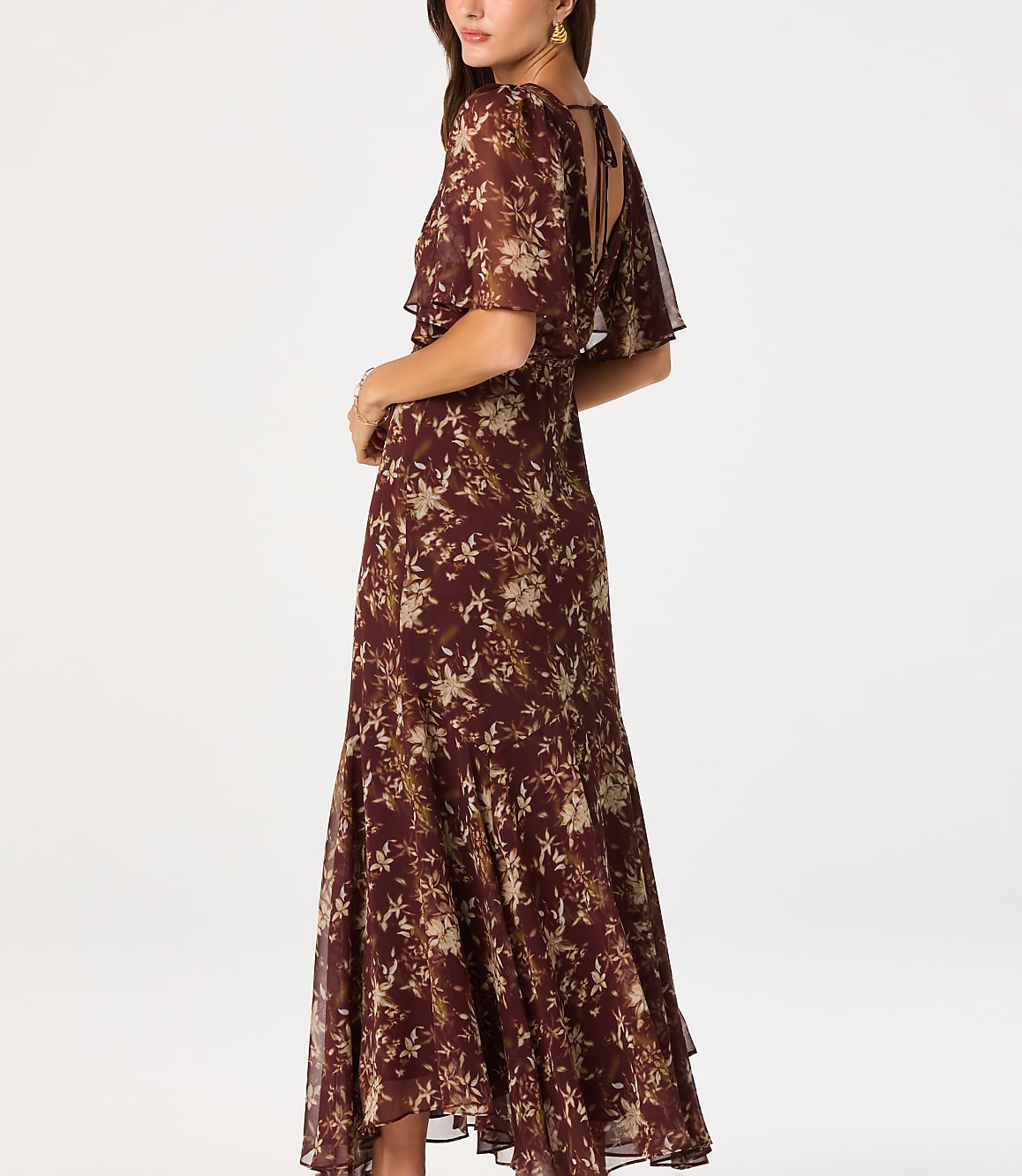 A woman in a floral print dress stands against a plain white background.