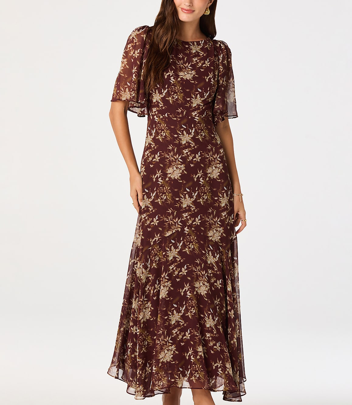 A woman in a floral dress stands against a plain white background.