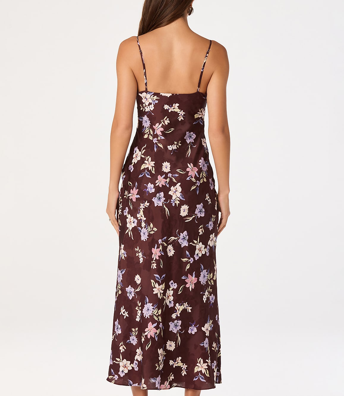 A woman in a floral slip dress stands against a plain white background.
