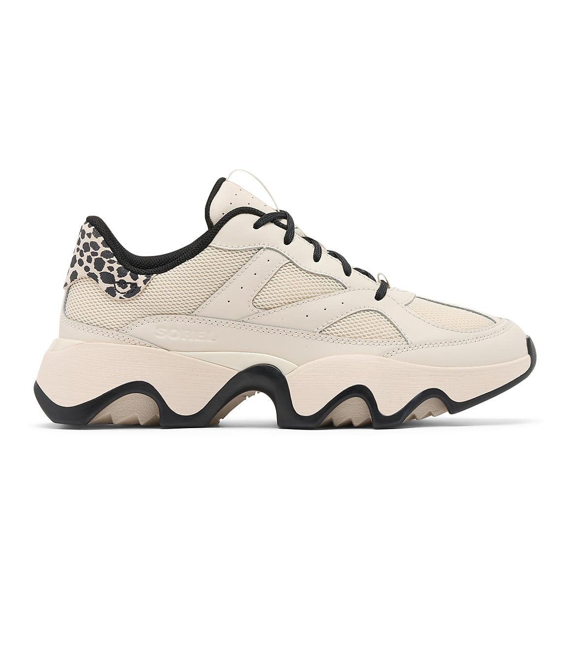 A cream-colored sneaker with black laces and a leopard-print heel tab rests on a plain white background.