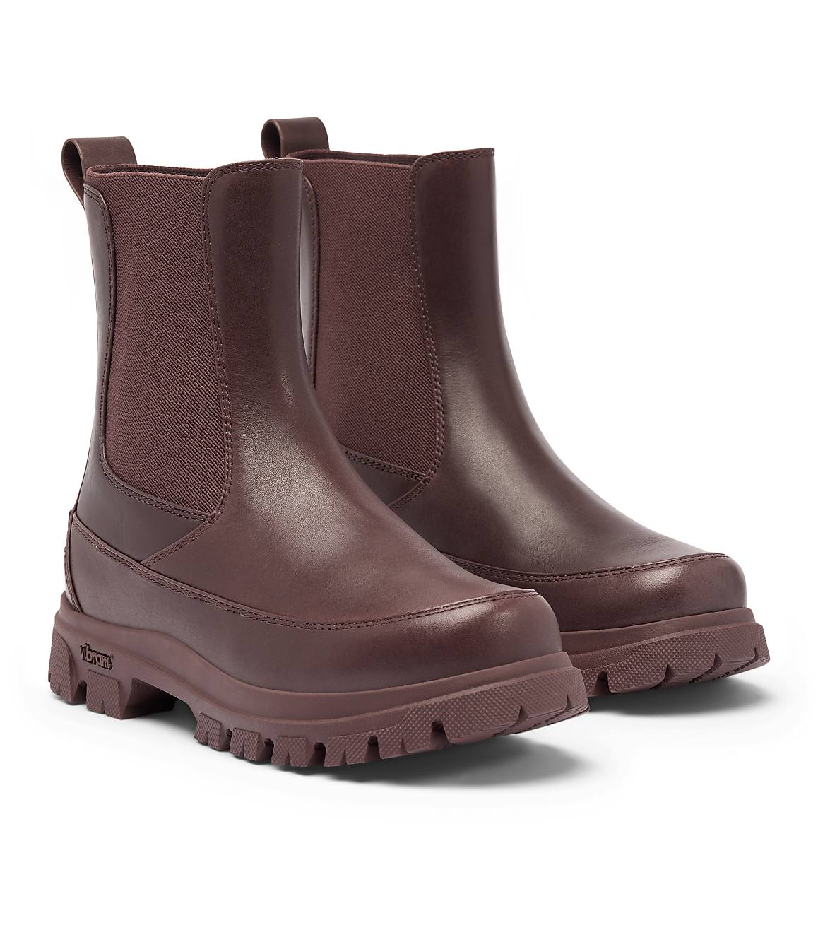 A pair of burgundy leather Chelsea boots with thick lug soles stand on a white background.
