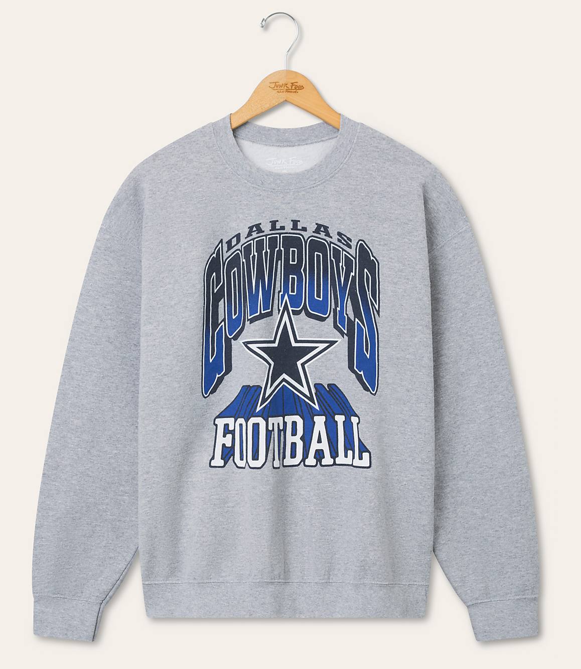 A gray Dallas Cowboys football sweatshirt hangs on a hanger against a plain, light-colored background.