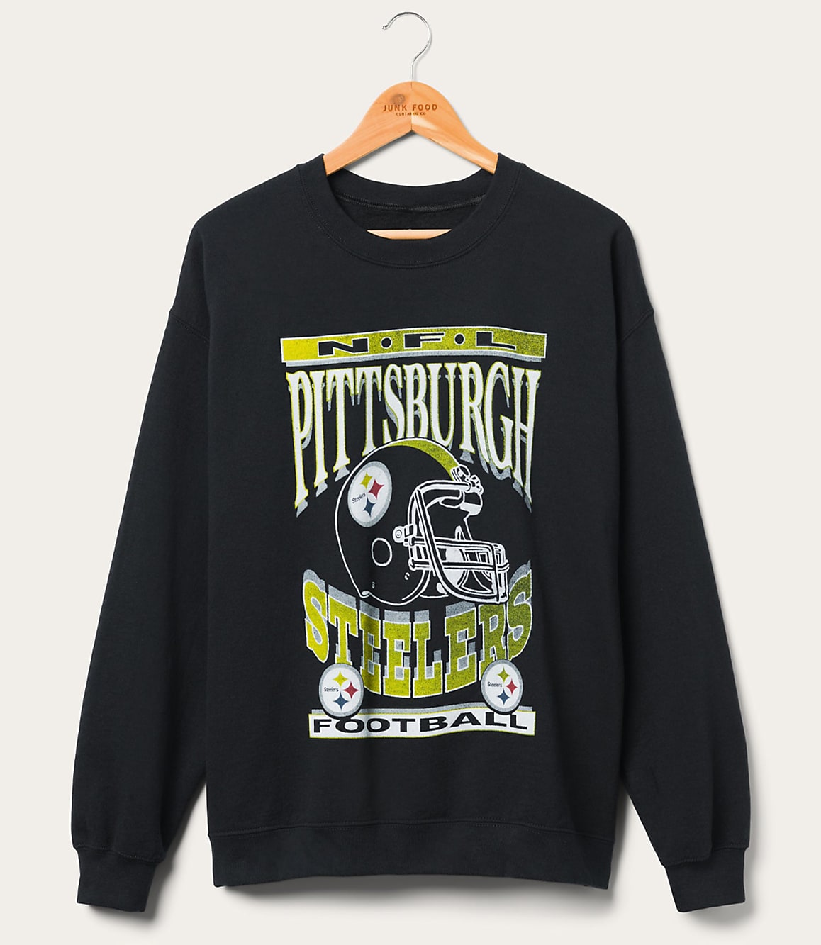 A black Pittsburgh Steelers sweatshirt with a graphic of a helmet and team name hangs on a wooden hanger against a plain white background.