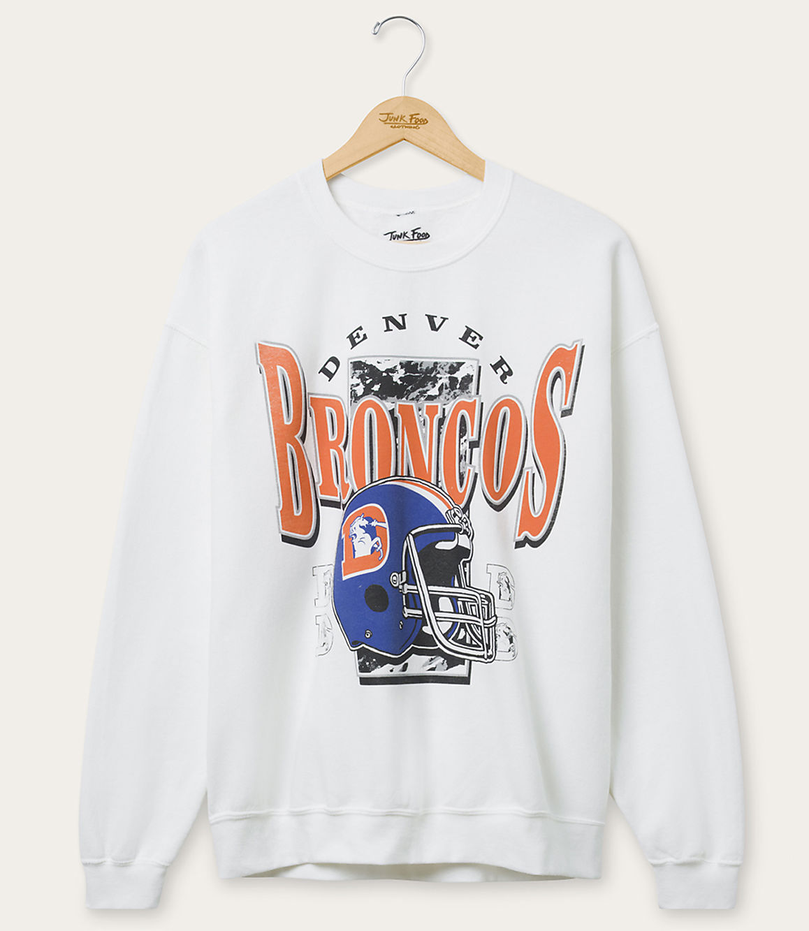 A white crewneck sweatshirt with a Denver Broncos graphic featuring a helmet and team name hangs on a wooden hanger against a plain light gray background.