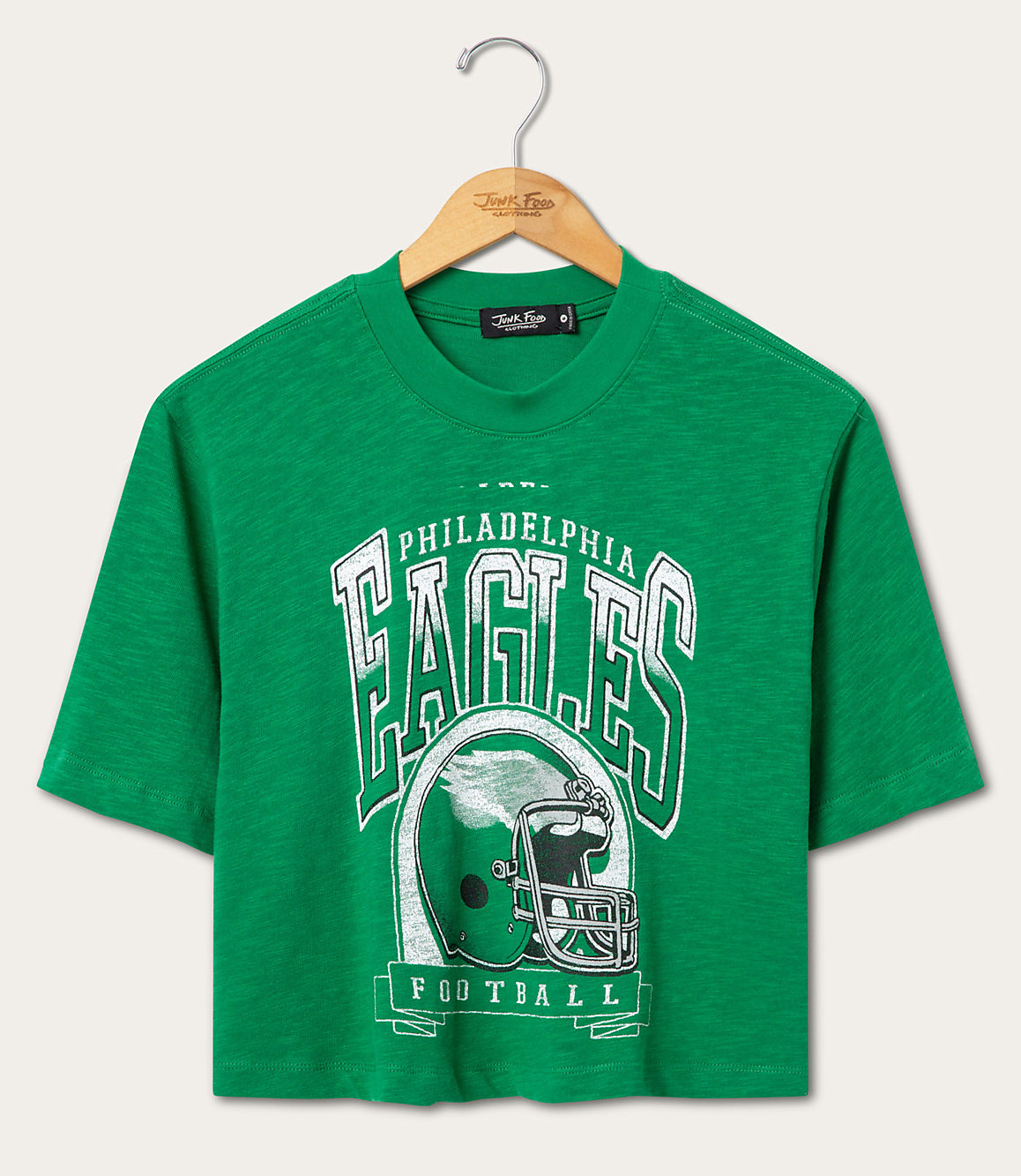 A green Philadelphia Eagles football t-shirt hangs on a wooden hanger against a plain white background.
