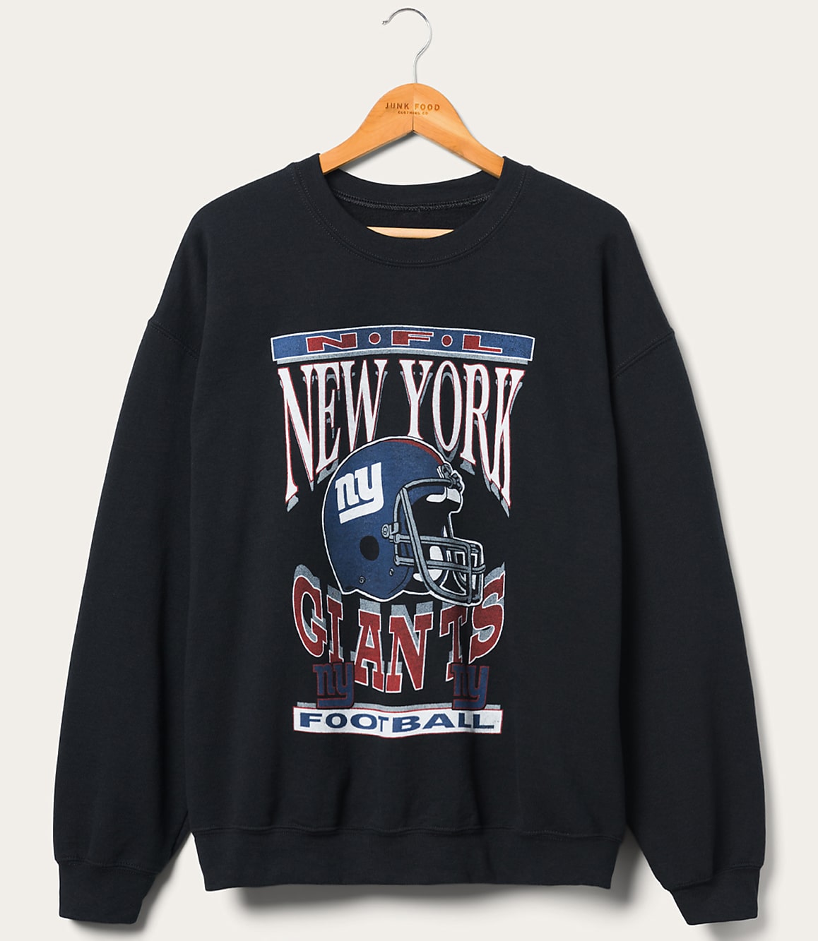 A dark blue New York Giants sweatshirt with a graphic of a helmet and team name is displayed on a wooden hanger against a plain, light-colored background.
