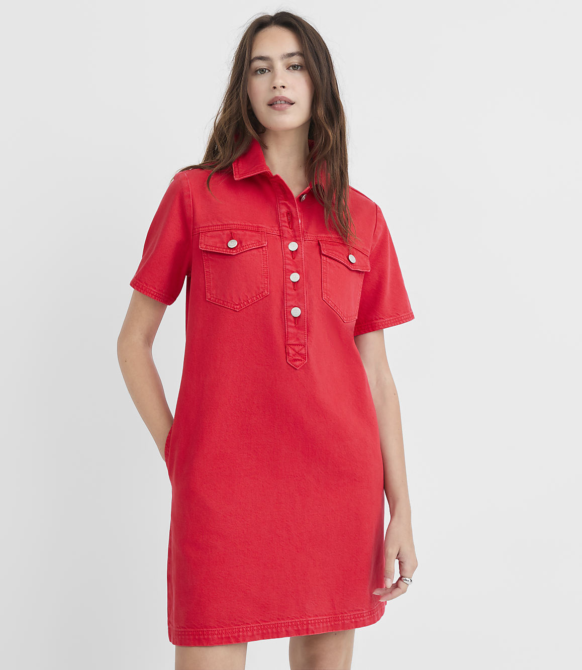 A woman in a red denim shirtdress stands against a plain white background.