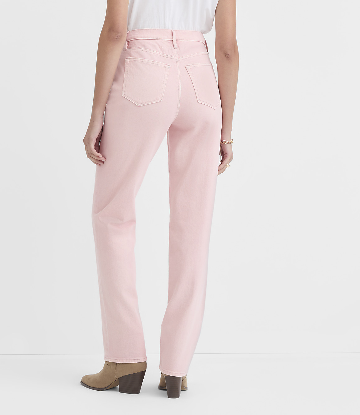 A person wearing light pink jeans and brown boots stands against a plain white background.