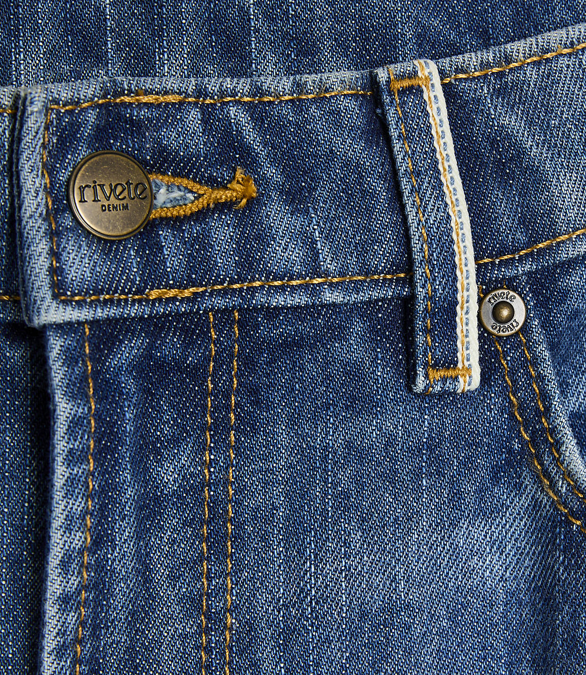 A close-up of blue denim jeans features a brass button with "rivete DENIM" on the left and a small metal rivet on the right, with yellow stitching throughout.