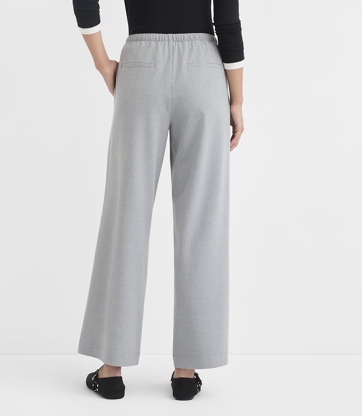 A person stands in light gray wide-leg pants and black flats against a plain white background.