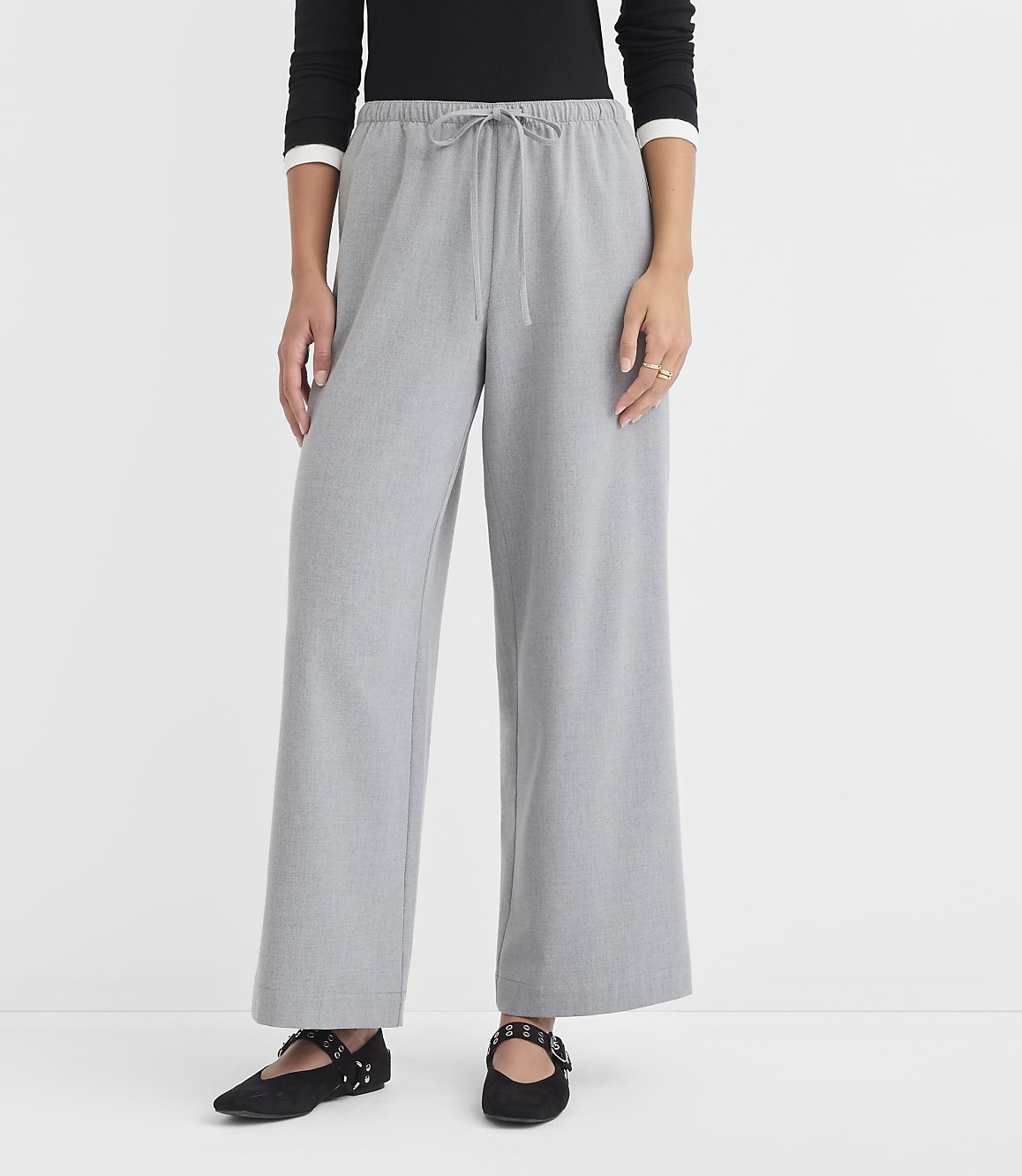 A person stands in light gray wide-leg pants and black flats against a plain white background.