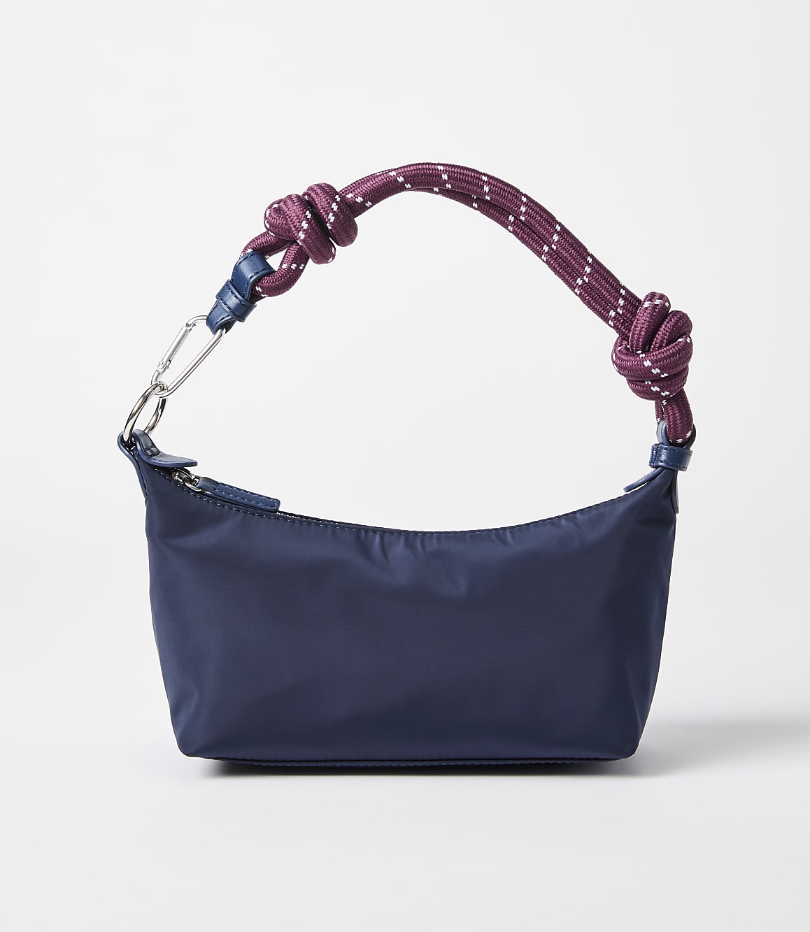 A navy blue crescent-shaped handbag with a knotted rope strap rests on a plain white background.