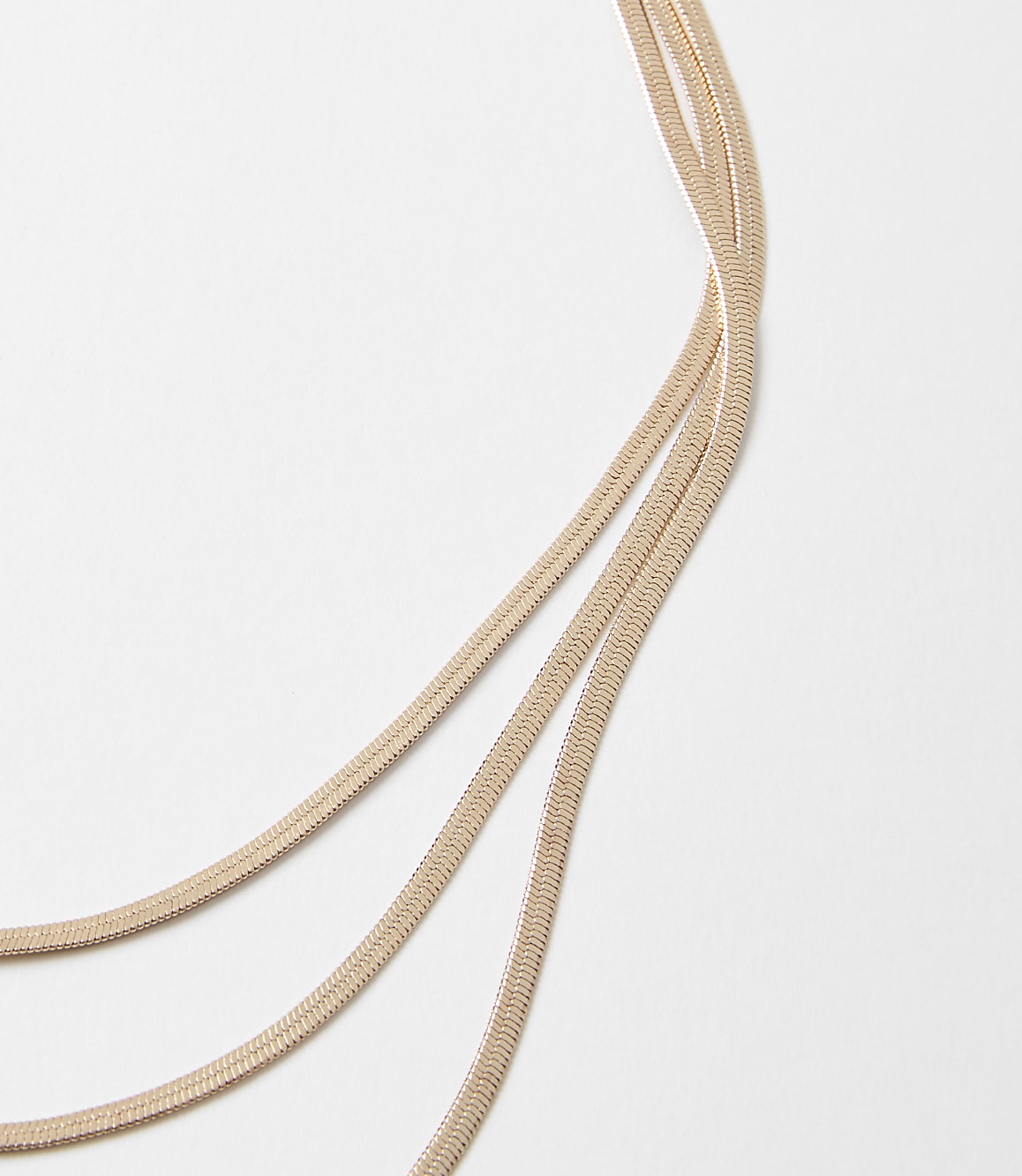 Three delicate rose gold chains curve across a plain white background.