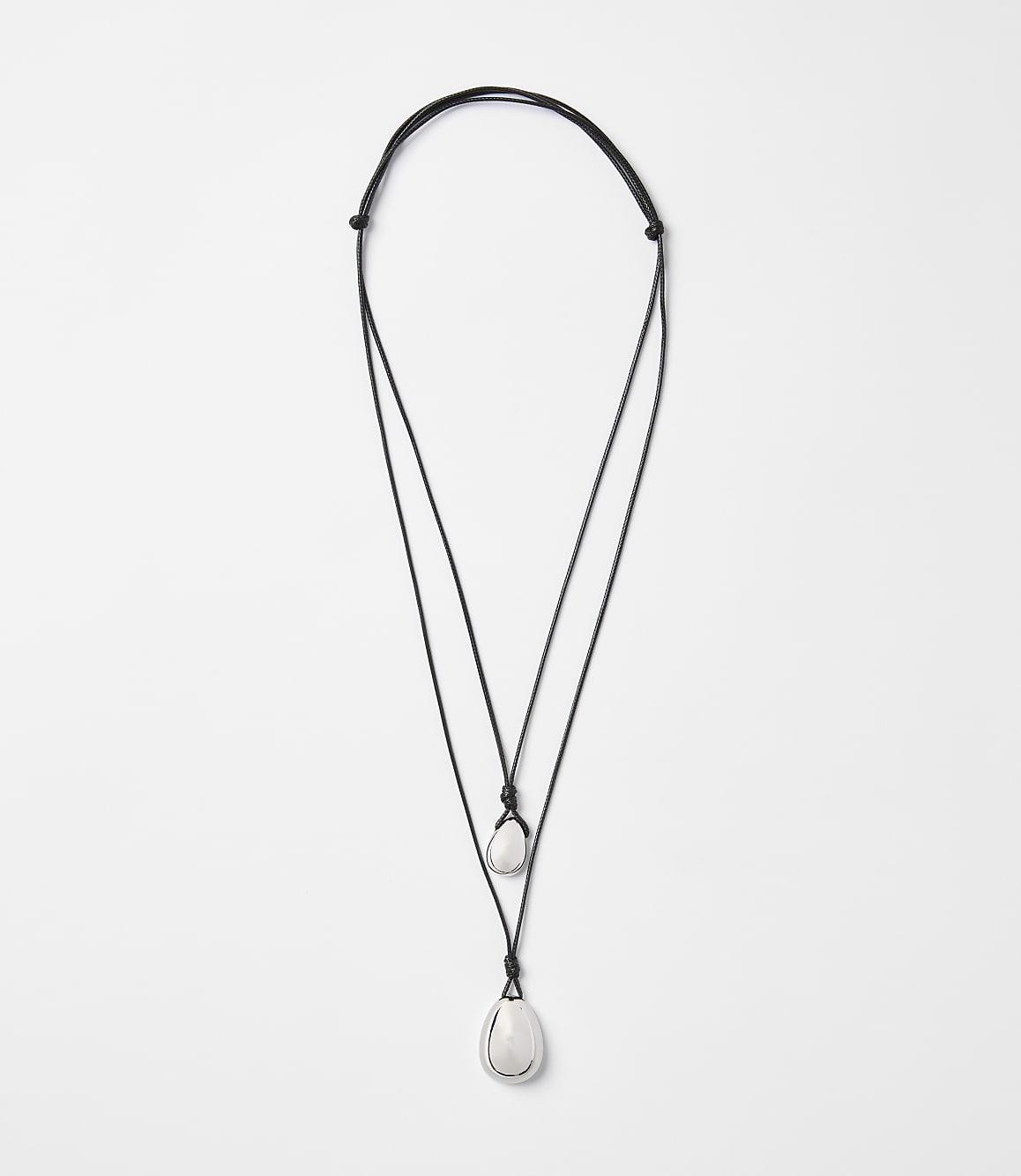 A delicate, layered necklace with two smooth, white stones hangs against a plain white background.