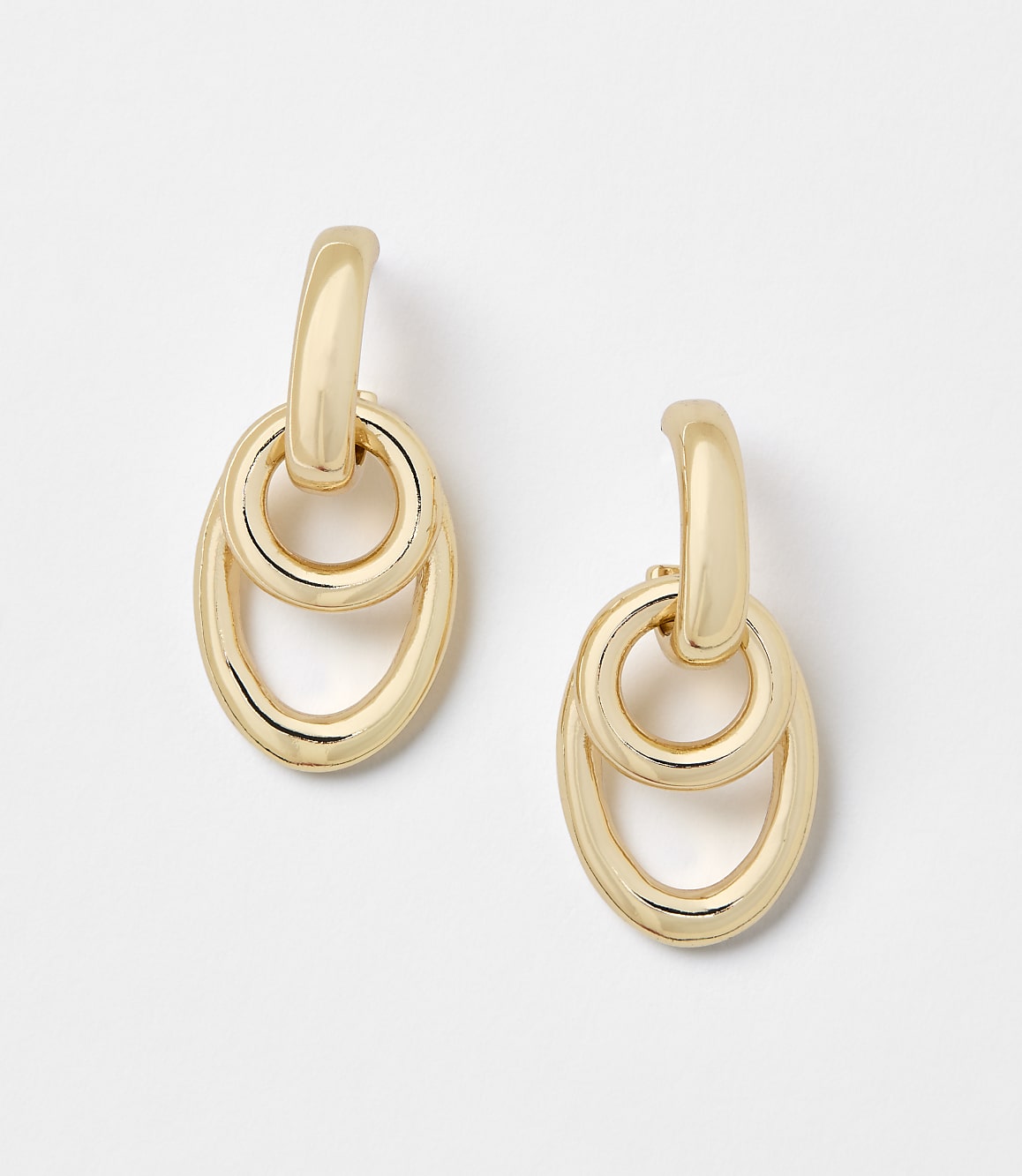 A pair of gold oval link earrings hang against a plain white background.