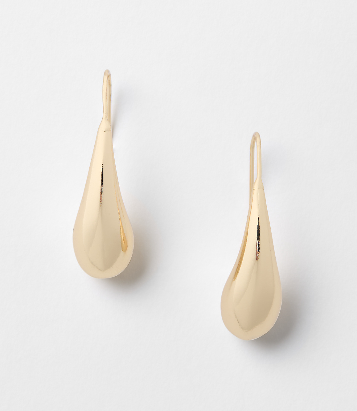 A pair of gold teardrop earrings hang against a plain white background.