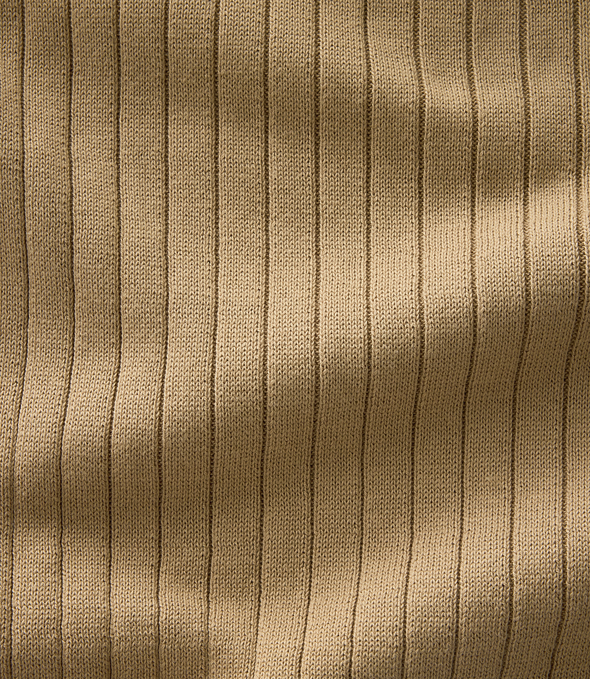 A close-up view of ribbed, tan fabric with soft shadows creating a textured background.