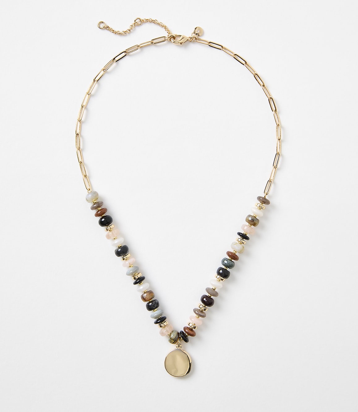 A gold chain necklace with a colorful assortment of stone beads and a pale pendant hangs against a plain white background.
