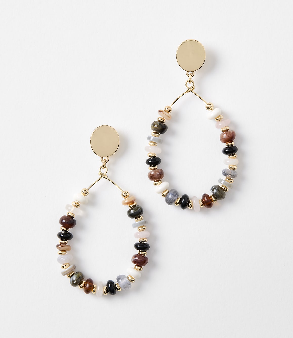 A pair of oval-shaped earrings with colorful beads and gold accents hang against a plain white background.
