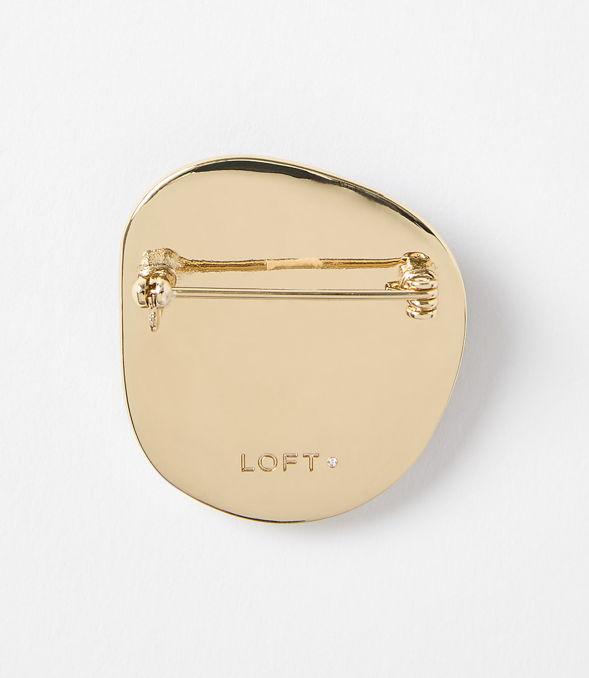A gold-toned, irregularly shaped brooch with a pin backing is centered against a plain white background.