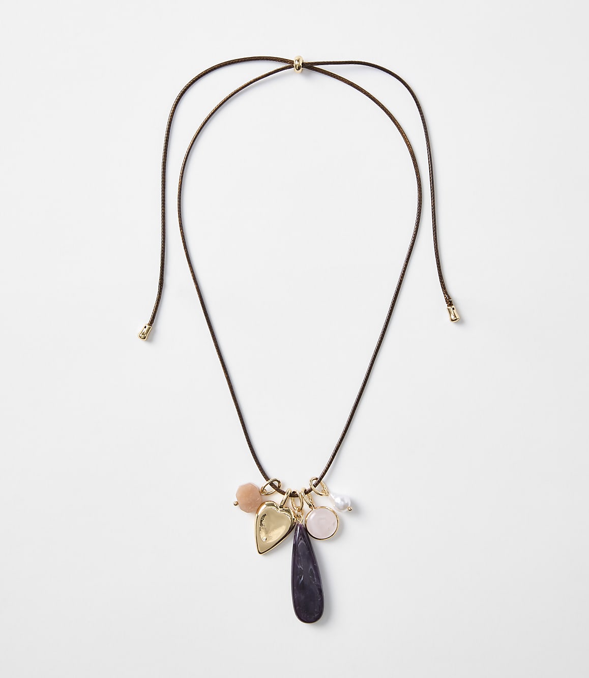 A delicate brown cord necklace with various charms, including a heart and a teardrop-shaped stone, hangs against a plain white background.