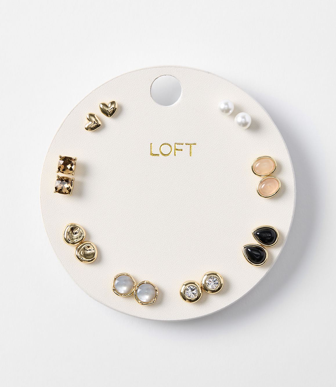 A white circular card displays a collection of assorted earrings, with a plain white background.