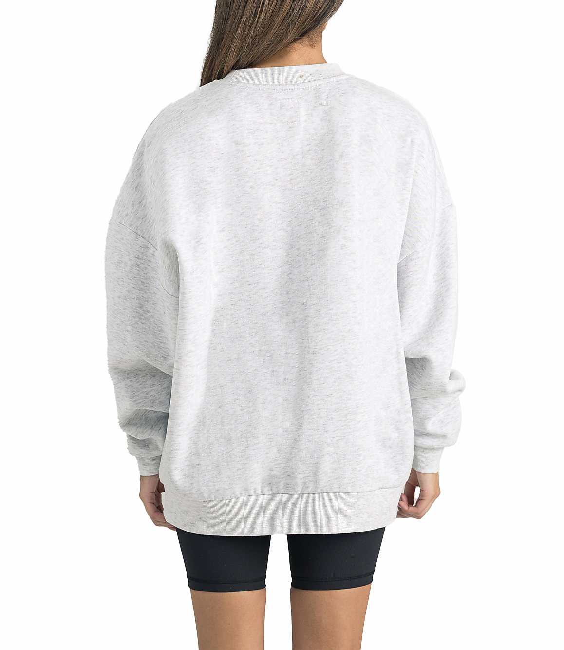 A person wearing a light gray sweatshirt and black shorts stands against a plain white background.