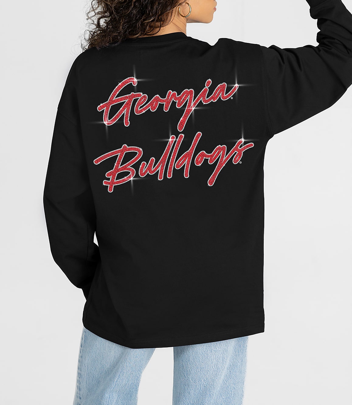 A person in a black long-sleeved shirt with "Georgia Bulldogs" in glittery red script on the back stands against a plain white background.