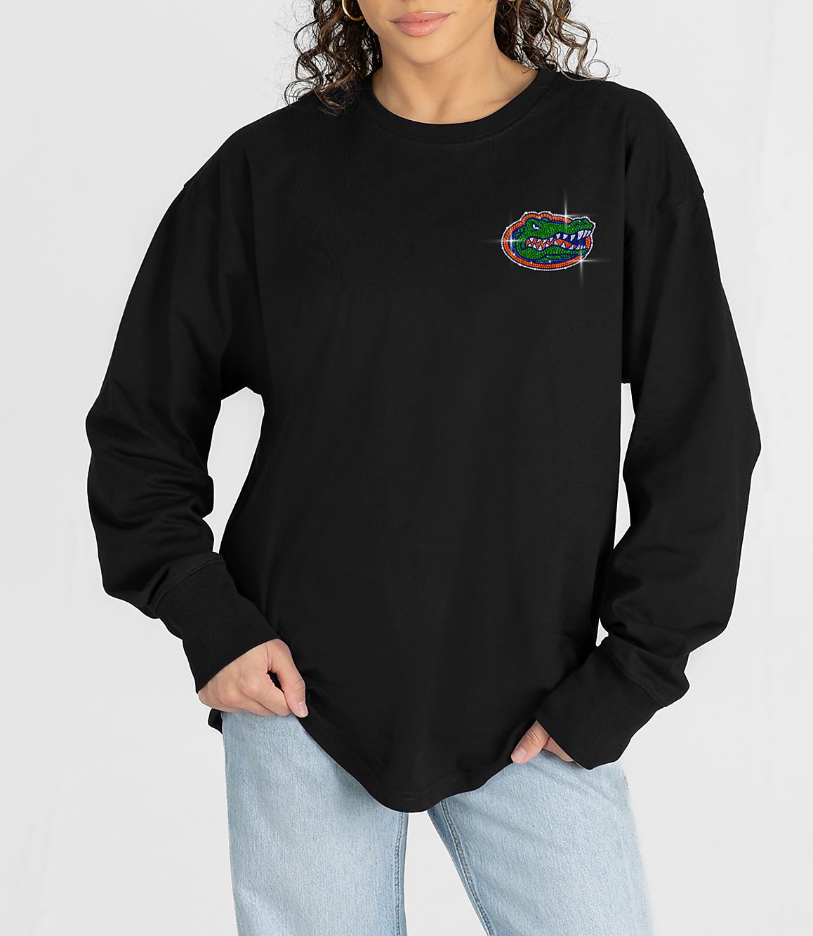 A person in a black long-sleeved shirt with a small Florida Gators logo on the chest stands against a plain white background.