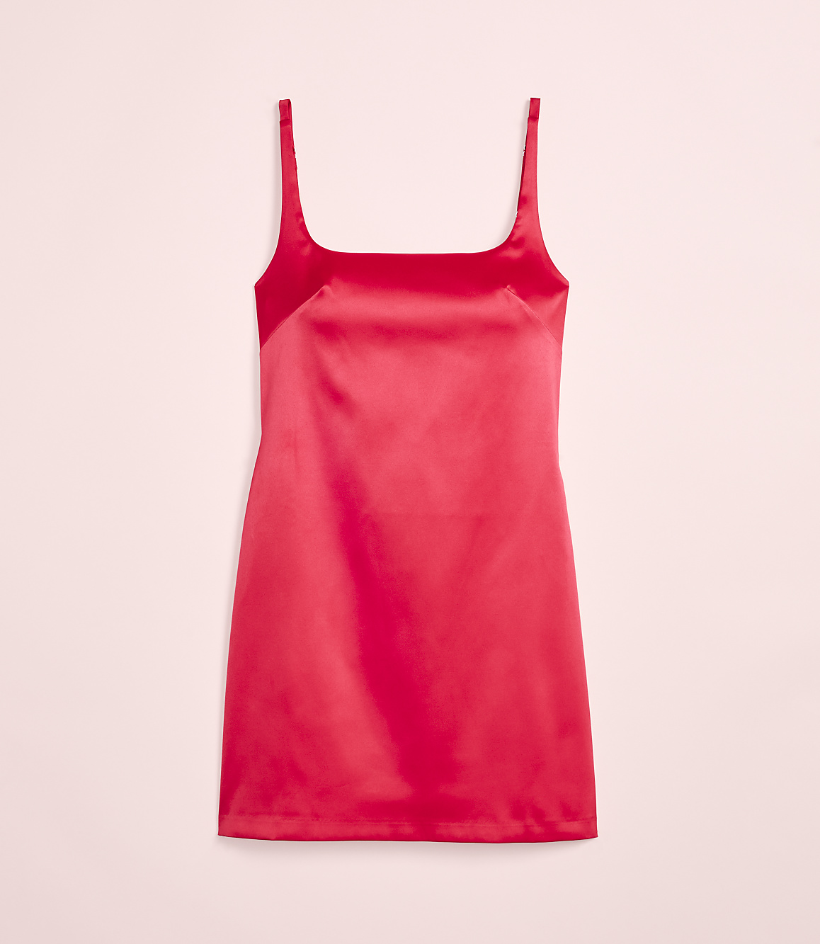 A vibrant red satin slip dress hangs against a soft pink background.