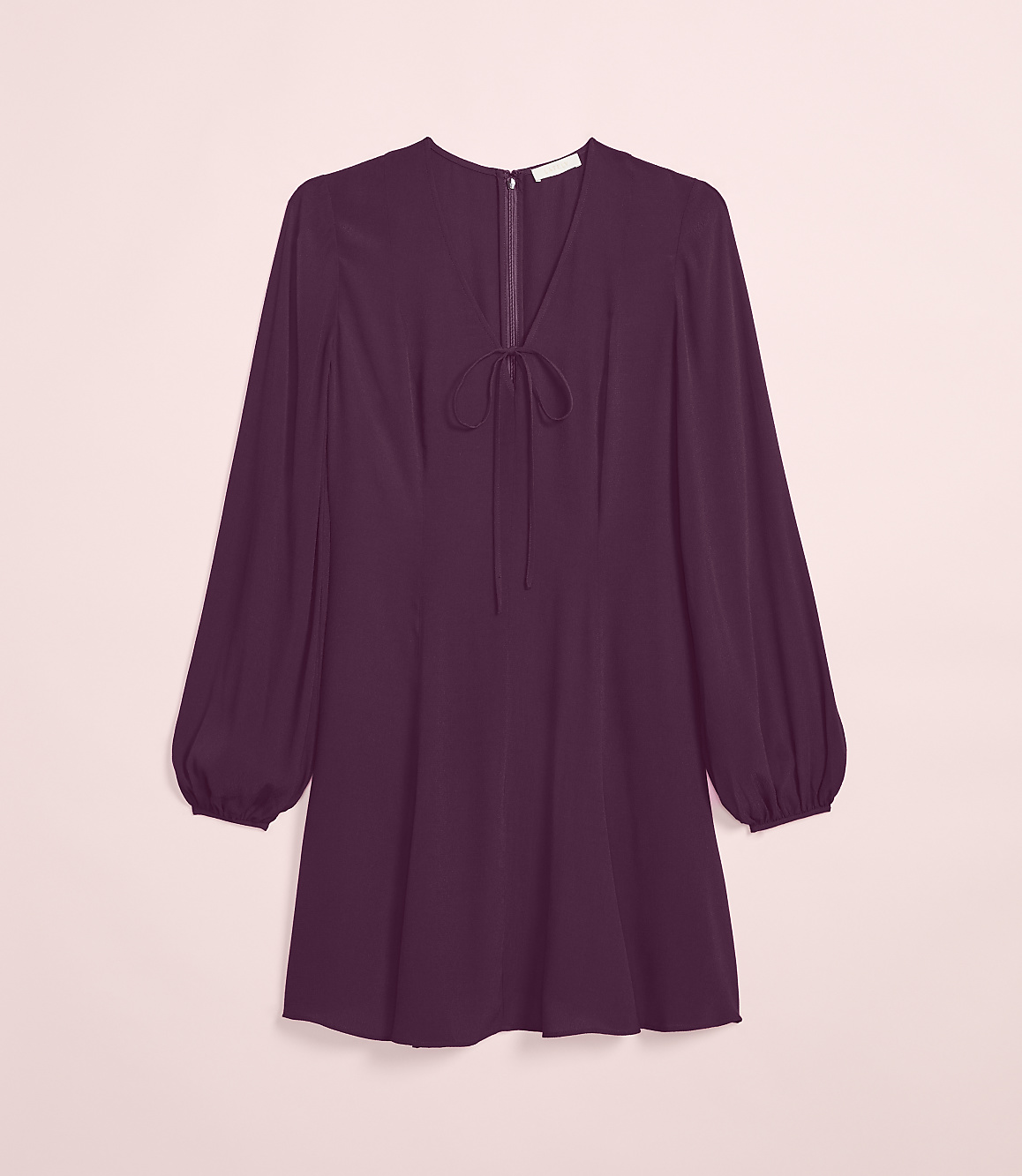 A plum-colored dress with a tie-neck detail and balloon sleeves hangs against a soft pink background.
