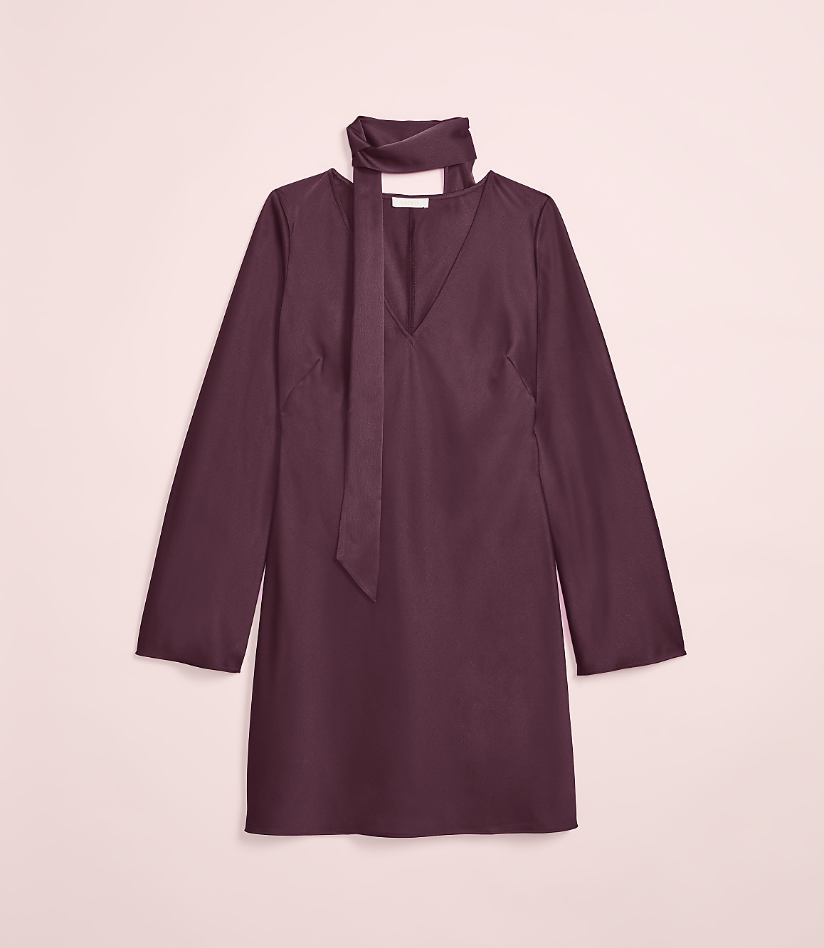 A plum-colored dress with a tie neck is laid flat against a soft pink background.