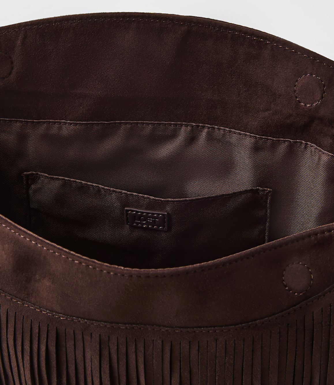 A brown suede fringed clutch with a satin lining and a small logo tag is presented against a plain white background.