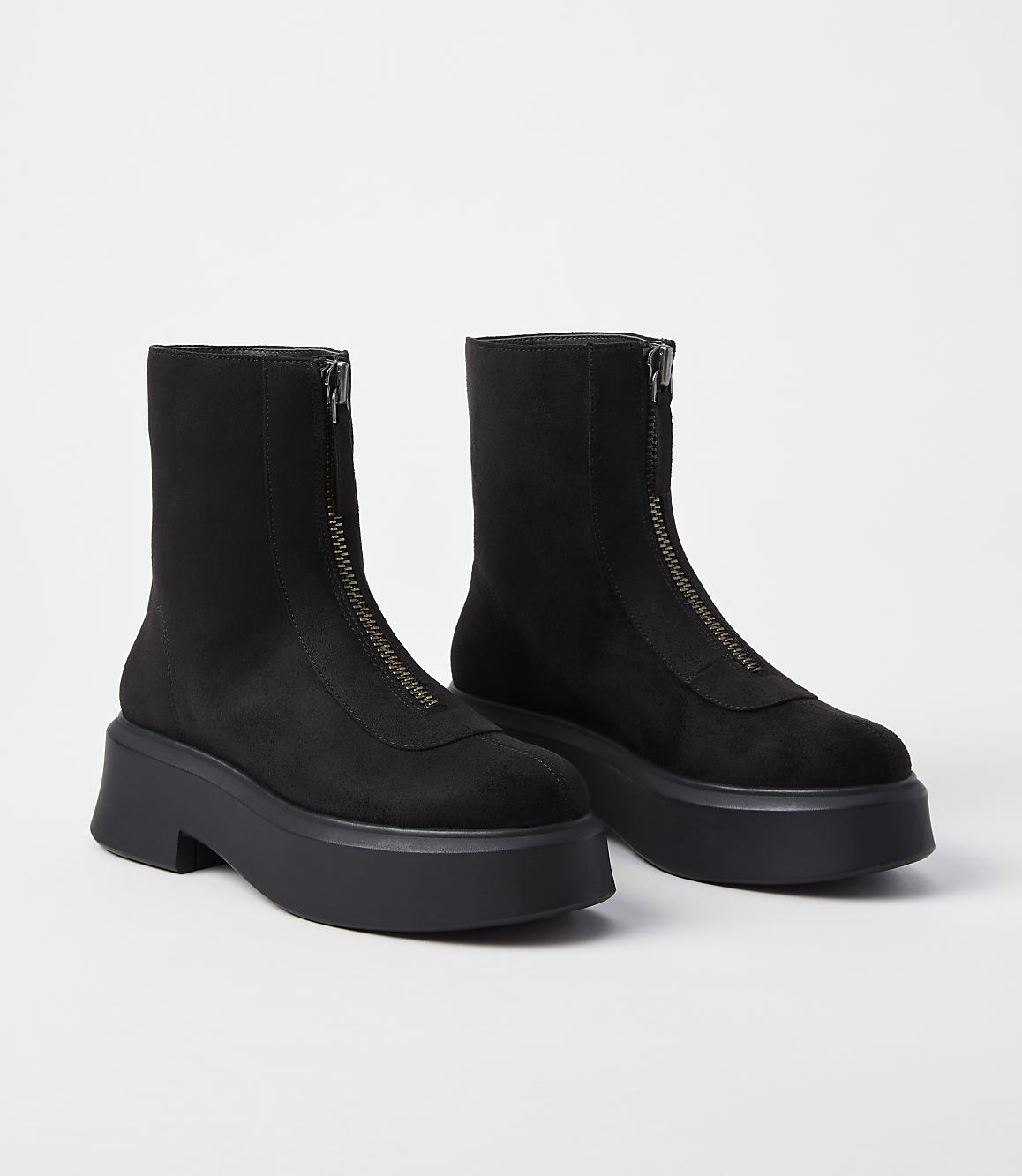A pair of black, zip-front platform boots rests on a plain white background.