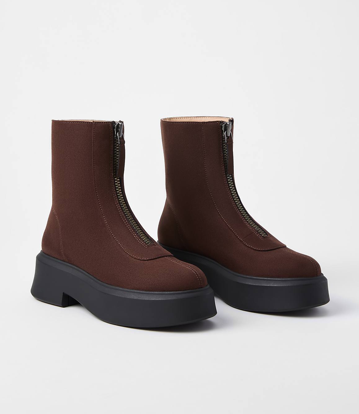 A pair of brown zip-up ankle boots with thick black platform soles are displayed against a plain white background.